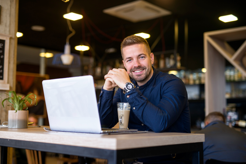 Smiling business owner using a laptop at a café, symbolizing early-stage business exit planning with Ventariom Advisory.